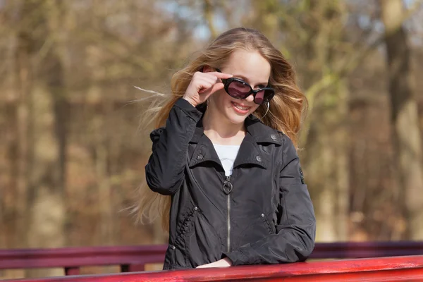 Smiling young blonde girl with sunglasses and braces in park. — Stock Photo, Image