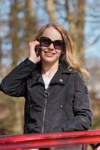 Young blonde girl with sunglasses in park calling with cellphone — Stock Photo, Image