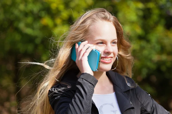 Jeune fille blonde avec bretelles dans le parc appelant avec téléphone mobile . — Photo