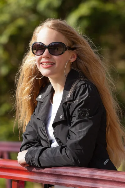 Jovem com cabelo loiro longo e óculos de sol na ponte no par — Fotografia de Stock