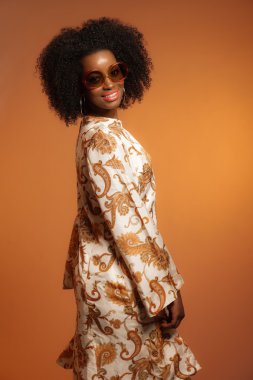 Retro 70s fashion african woman with paisley dress and sunglasse clipart