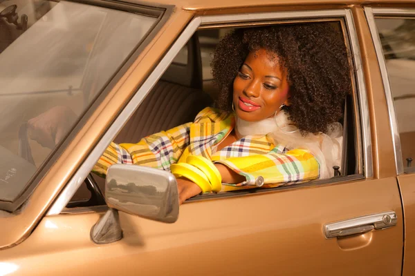 Retro 70s fashion african american woman driving in gold seventi — Stock Photo, Image