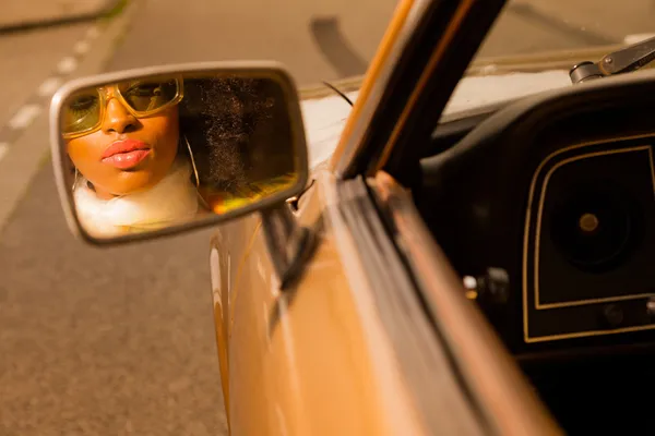 Retro 70s afro moda mujer con gafas de sol mirando en espejo o —  Fotos de Stock