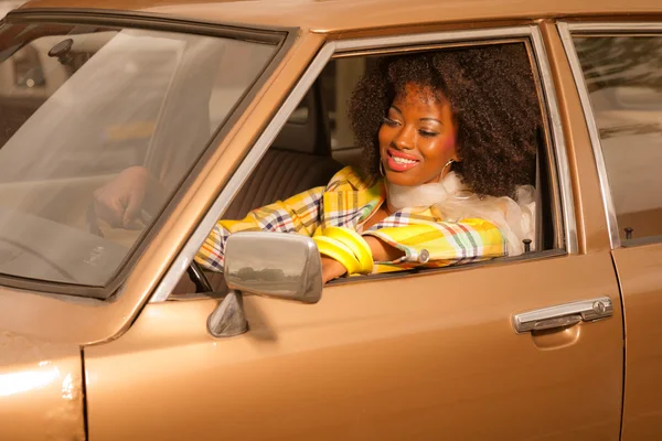 Retro 70s fashion african american woman driving in gold seventi — Stock Photo, Image