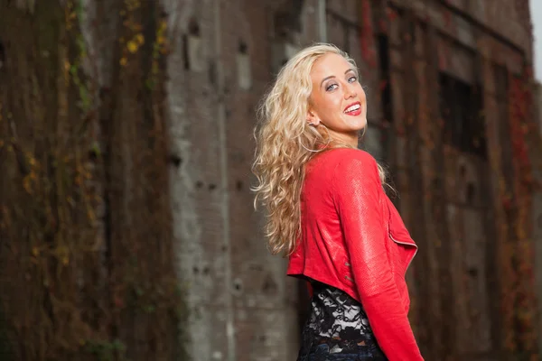 Mujer joven guapa con pelo largo y rubio y chaqueta roja. Urbano —  Fotos de Stock