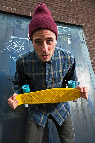 Louco skate expressivo com chapéu de lã segurando seu skateboa — Fotografia de Stock