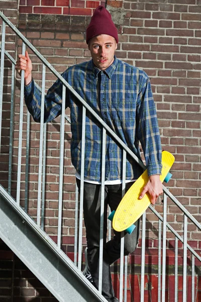 Δροσερό skateboarder με μάλλινο καπέλο εκμετάλλευση του skateboard standin — Φωτογραφία Αρχείου