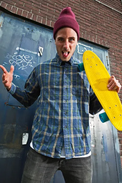 Mad expressive skateboarder with woolen hat holding his skateboa — Stock Photo, Image