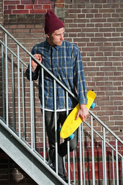 Cool skateboardista s vlněnou čepici drží jeho skateboard standin — Stock fotografie