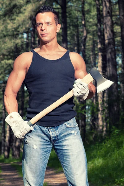 Muscled man with black shirt and axe in forest. — Stock Photo, Image