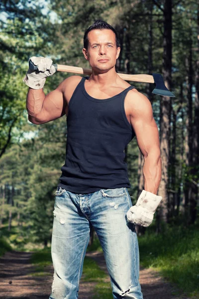 Muskulöser Mann mit schwarzem Hemd und Axt im Wald. — Stockfoto