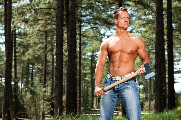 Sin camisa musculoso fitness leñador hombre con hacha en el bosque . —  Fotos de Stock