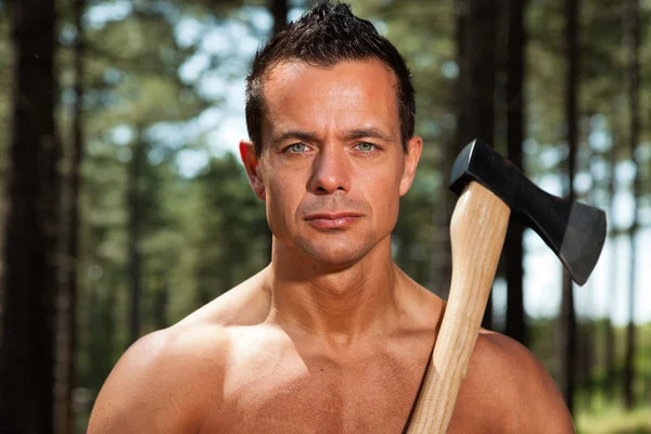 Uomo boscaiolo fitness muscoloso senza maglietta con ascia nella foresta . — Foto Stock