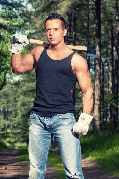 Uomo muscoloso con camicia nera e ascia nella foresta . — Foto Stock