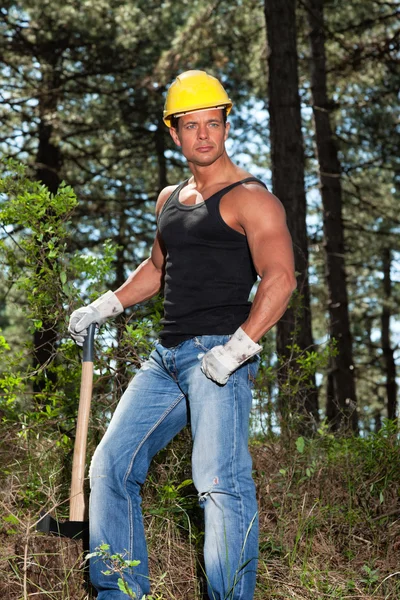 Muscled lumberjack with black shirt and axe in forest. Wearing y — Stock Photo, Image