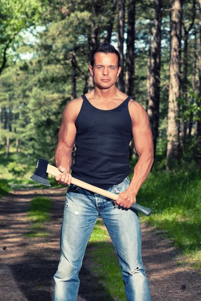 Homme musclé avec chemise noire et hache en forêt . — Photo