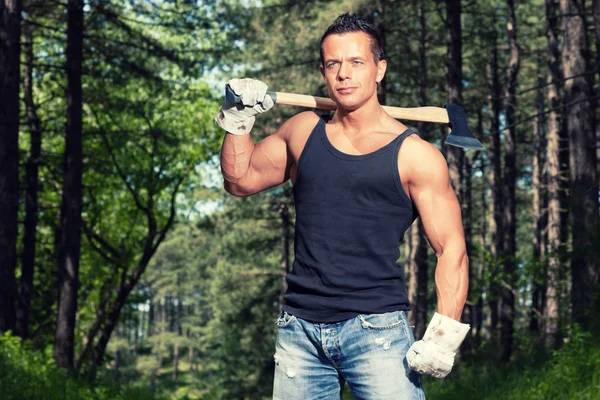 Homem musculado com camisa preta e machado na floresta . — Fotografia de Stock