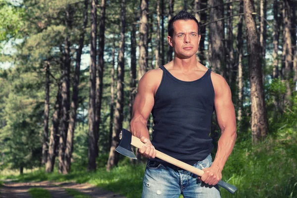 Muscled man with black shirt and axe in forest. — Stock Photo, Image