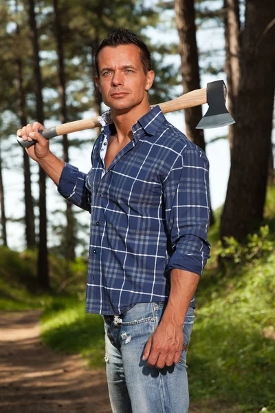 Bonito homem forte lenhador segurando machado. Vestindo camisa azul . — Fotografia de Stock