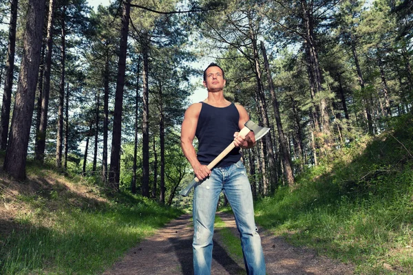 Homem musculado com camisa preta e machado na floresta . — Fotografia de Stock