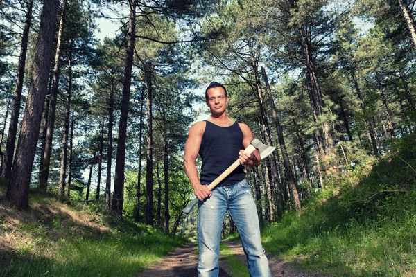 Muscled man with black shirt and axe in forest. — Stock Photo, Image