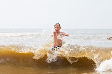Okyanus dalgaları ile oynayan bir çocuk.
