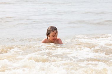 Okyanus dalgaları ile oynayan bir çocuk.