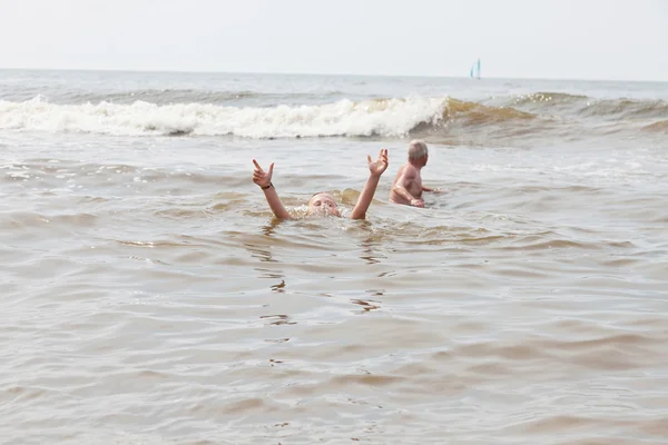 Young boy and grandpa swimming in the ocean. Enjoying the waves. — Stock Photo, Image