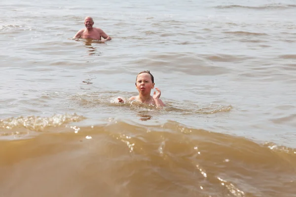 Rapaz e avô nadando no oceano. Aproveitando as ondas . — Fotografia de Stock