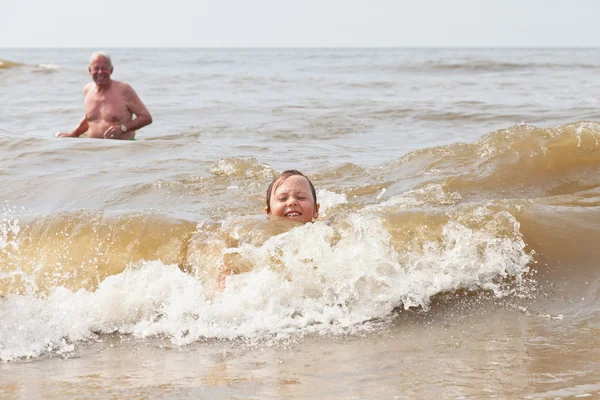Niño y abuelo nadando en el océano. Disfrutando de las olas . —  Fotos de Stock