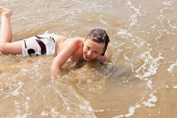 Junge amüsiert sich am Strand in den Wellen des Ozeans. — Stockfoto