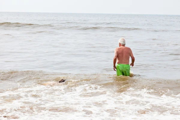 Senior nyugdíjas férfi sétál a vízben a strandon. — Stock Fotó