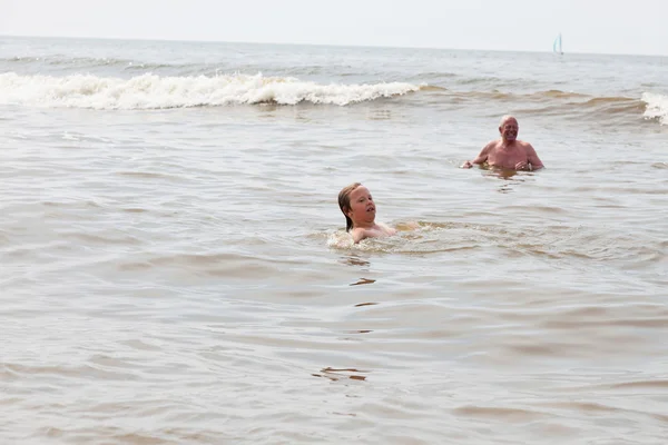 Young boy and grandpa swimming in the ocean. Enjoying the waves. — Stock Photo, Image