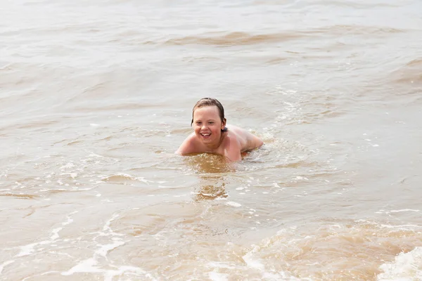 Jeune garçon célibataire jouant dans l'océan avec des vagues . — Photo