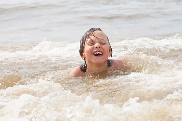 Mladej kluk baví na pláži ve vlnách oceánu. — Stock fotografie