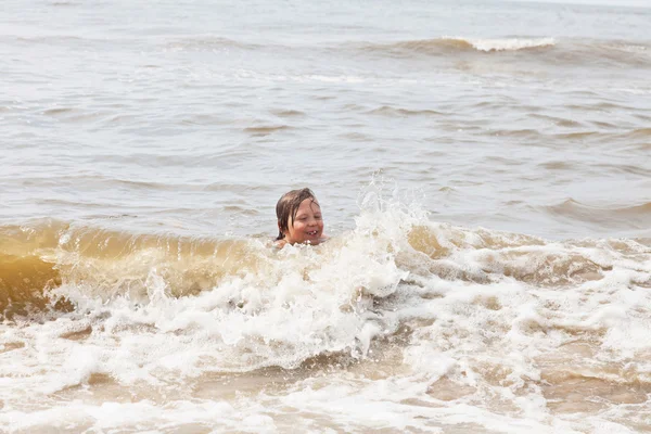 Mladej kluk baví na pláži ve vlnách oceánu. — Stock fotografie