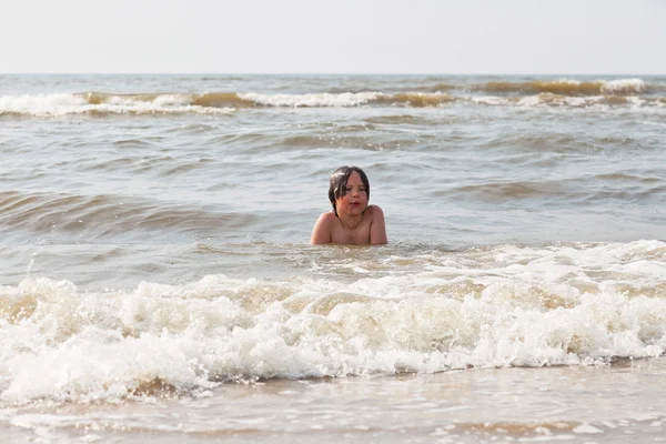 Anak laki-laki bersenang-senang di pantai dalam gelombang laut . — Stok Foto