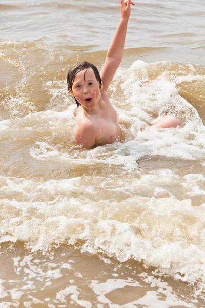 Kid jongen plezier op het strand in de golven van de Oceaan. — Stockfoto