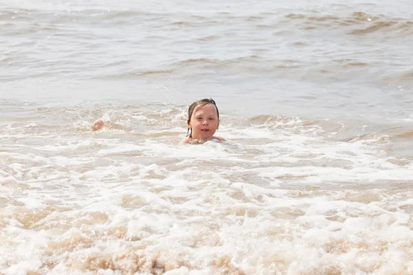 Mladej kluk baví na pláži ve vlnách oceánu. — Stock fotografie