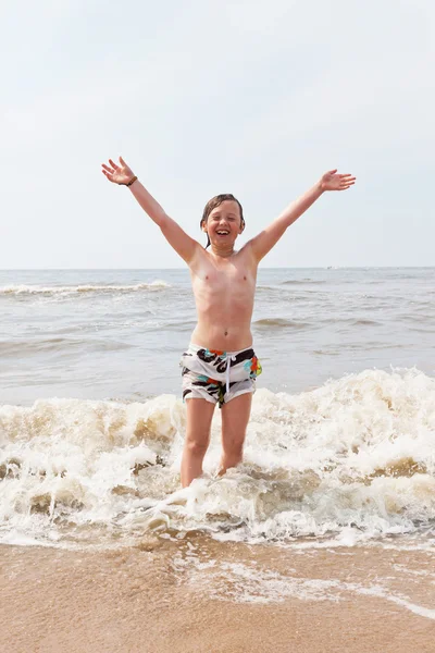 Kid jongen plezier op het strand in de golven van de Oceaan. — Stockfoto