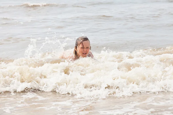 Niño divirtiéndose en la playa en las olas del océano . — Foto de Stock