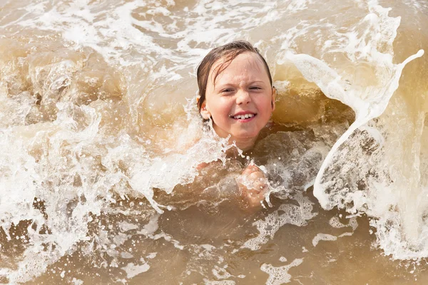 海の波のビーチで楽しんで子供男の子. — Stockfoto