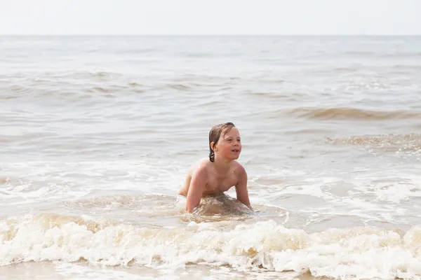 Junge amüsiert sich am Strand in den Wellen des Ozeans. — Stockfoto