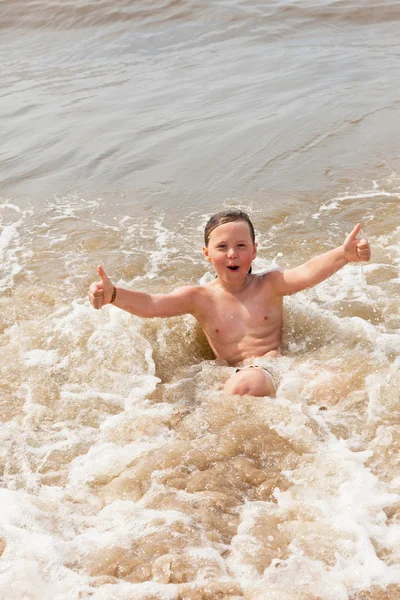 Kid jongen plezier op het strand in de golven van de Oceaan. — Stockfoto