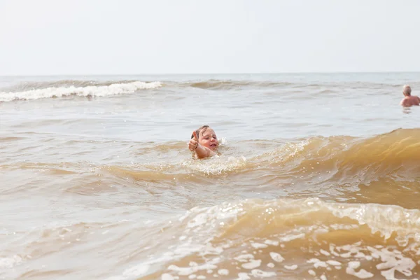 Un niño jugando en el océano con olas . — Foto de Stock