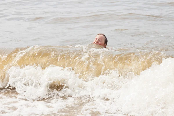 Jovem solteiro brincando no oceano com ondas . — Fotografia de Stock
