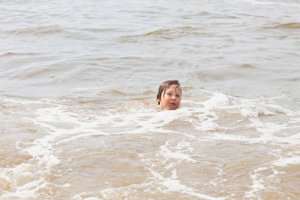 Gyerek fiú szórakozás a strandon, a hullámok az óceánon. — Stock Fotó