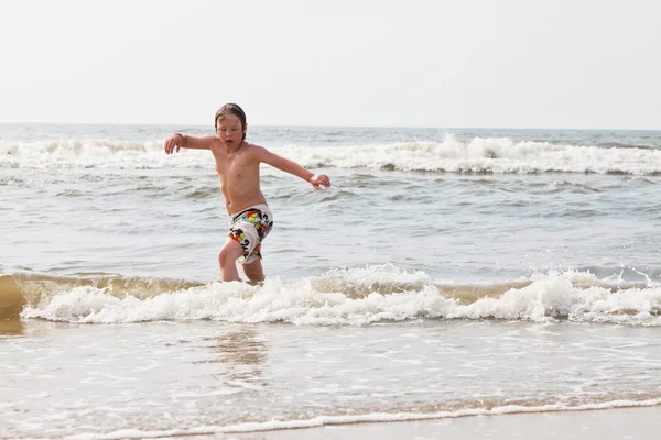 Niño parado en el agua en la playa . — Foto de Stock