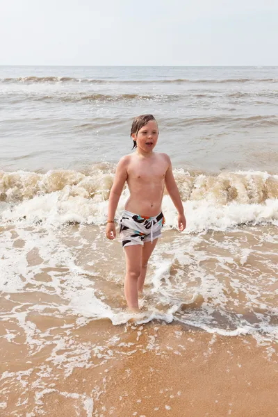 Kid jongen plezier op het strand in de golven van de Oceaan. — Stockfoto