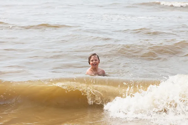 Chłopiec dziecko, zabawy na plaży, fale oceanu. — Zdjęcie stockowe